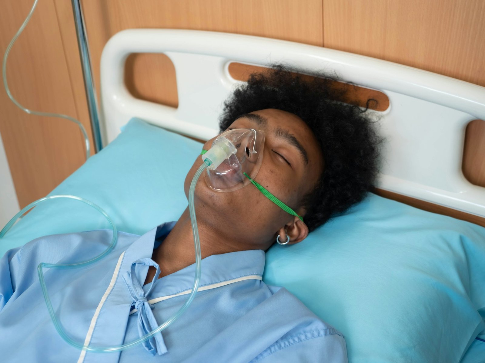 At hospital intensive care unit patient in coma lay on bed unconsciousness breathing to oxygen mask